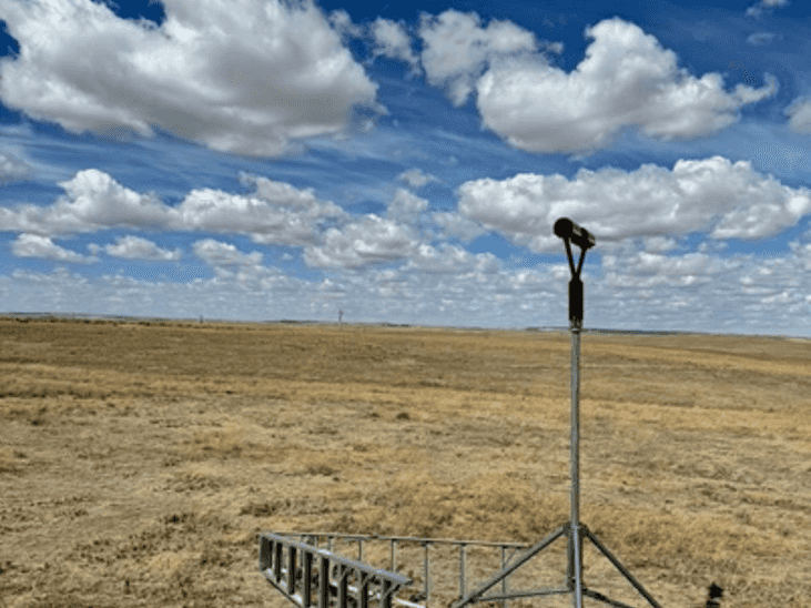 A picture of a laser-based disdrometer in a field.