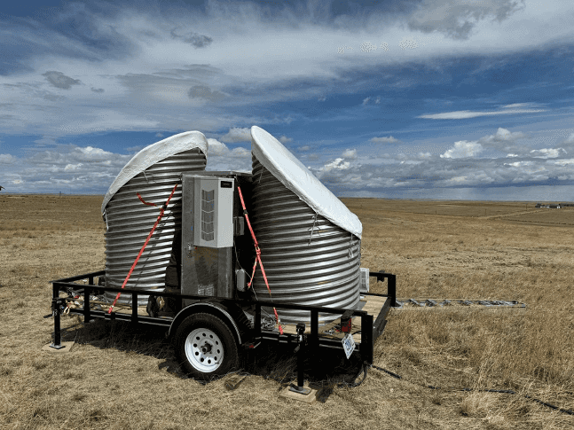 A picture of a two large drums with white vinyl wrap over them that contain the NOAA snow level radar.